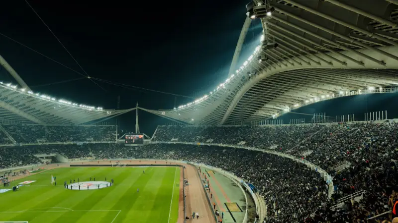 Razsvetljen nogometni stadion ponoči, poln gledalcev